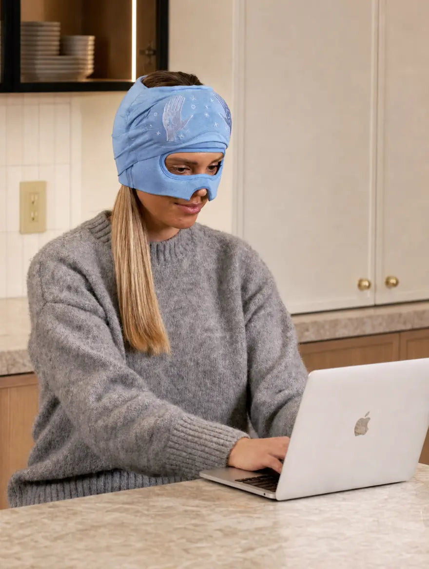 Working at a desk with the eye mask slid up, eyes open